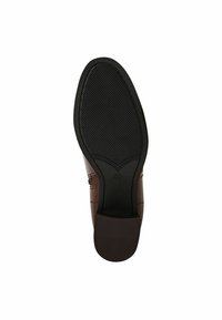Zapato de cuero marrón con una suela flexible de goma negra. La suela presenta líneas horizontales grabadas para un mejor agarre y un diseño de tacón bajo.