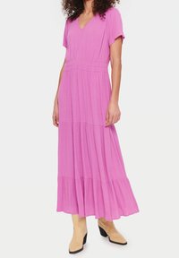 Dlouhé růžové šaty s krátkými rukávy, výstřihem do V a volánovou sukni. Vyrobeny z lehkého materiálu, mají elastický pas pro pohodlí.