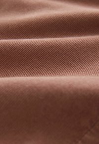 Brown fabric with a diagonal ribbed texture, showing soft and smooth folds. The material appears durable and slightly fuzzy.