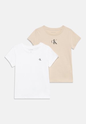 Two short-sleeve t-shirts, one white and one beige, both with small black Calvin Klein "cK" logos on the front.