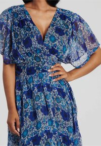 Blue floral dress with sheer, puffed sleeves and a deep V-neck. Features intricate floral patterns in shades of blue on a light background.