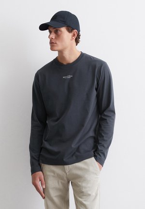 Donkerblauw overhemd met lange mouwen, gemaakt van katoen, met een ronde hals en een klein logo op de borst, gecombineerd met lichtgekleurde broek.