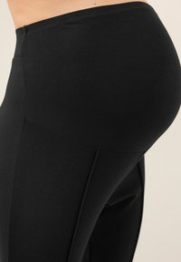 Leggings neri con una texture liscia, vita alta e dettagli di cuciture curve per un aspetto aderente.