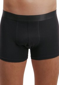 Boxer shorts neri in cotone con una cintura liscia e una vestibilità aderente, dotati di una tasca sagomata e gambe corte.