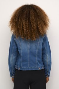 Veste en denim bleu moyen avec une finition délavée. Dotée de coutures verticales, de fermetures à boutons et d'un col classique. Coupe ajustée.