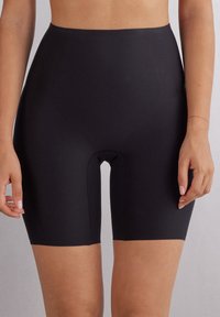Černé vysoké tvarující šortky vyrobené z elastického materiálu, s hladkou texturou a délkou do poloviny stehna, s výřezem ve středu.