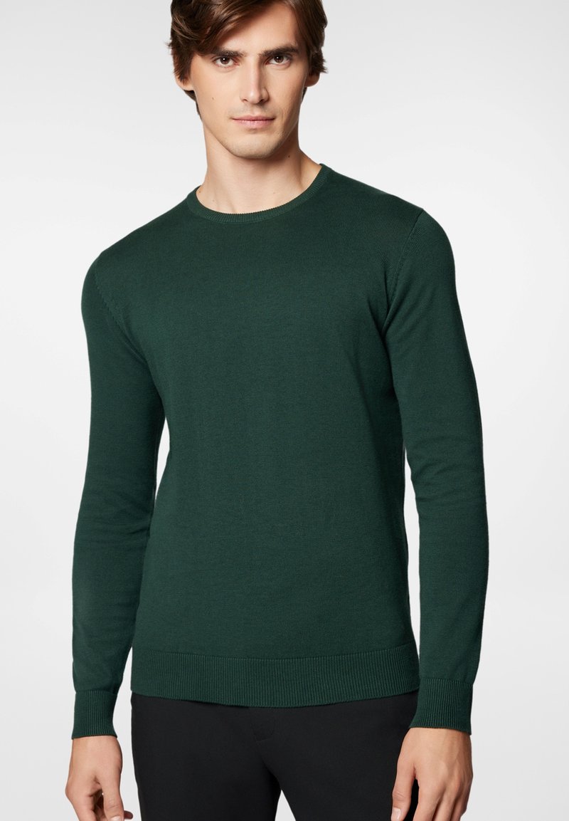 Ciemnozielony sweter z dzianiny z długimi rękawami, prążkowanym dekoltem, mankietami i dolnym wykończeniem. Charakteryzuje się gładką teksturą oraz dopasowanym krojem.