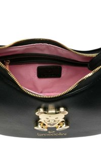 Borsa a mano in pelle nera con un accento a forma di orsacchiotto dorato, dotata di interno in tessuto rosa e chiusura con zip. Inclusi dettagli distintivi del logo.