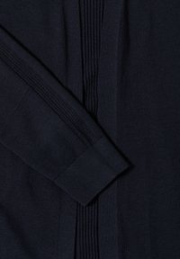 Manche de pull en maille bleu marine foncé avec poignet côtelé et détails côtelés verticaux le long du bras et du corps.