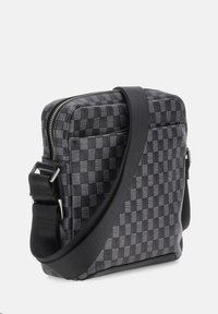 Borsa a spalla nera con motivo, dotata di zip e di una tracolla, di forma rettangolare. Realizzata in tessuto resistente con una texture liscia.