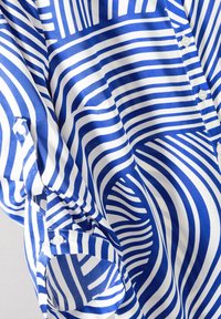 Camicia a maniche lunghe blu e bianca con motivi a righe ondulate, realizzata in tessuto morbido, con vestibilità rilassata e polsini abbottonati.