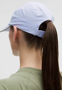 Gorra atlética de color púrpura claro con un diseño perforado, correa ajustable en la parte trasera y cabello recogido en una coleta.