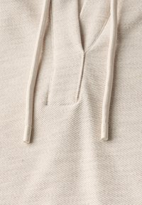 Ljusbeige hoodie-tyg med en strukturerad väv, försedd med en grund krage, snörning med plastspetsar och en liten logodetalj.