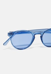 Modré plastové slnečné okuliare s okrúhlymi šošovkami, UV400 ochranou a priehľadným rámom. Majú jednoduchý dizajn bez viditeľných vzorov.