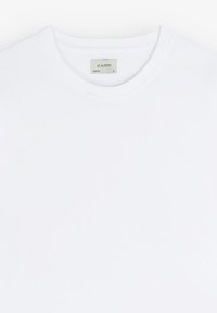 Camiseta blanca de manga corta hecha de algodón con cuello redondo. La etiqueta en el interior muestra "SCALPERS" y la talla "XL". Textura suave, sin estampados.