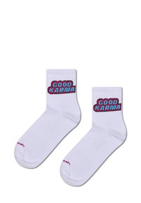 Hvide ankelstrømper med teksten "GOOD KARMA" i fed rød og blå skrift. Blødt stof med ribbet tekstur, designet til komfort.