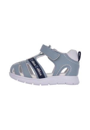 Lyseblå barnsandal lavet af syntetisk materiale, med velcrolukning, hvide detaljer og en tekstureret sål for bedre greb.