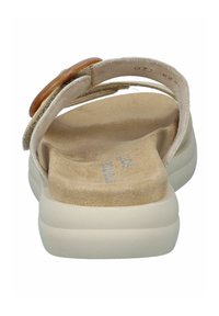 Sandale beige avec une sangle en daim doux et un accent arrondi couleur tan. Semelle intérieure légère et rembourrée et semelle large et confortable.