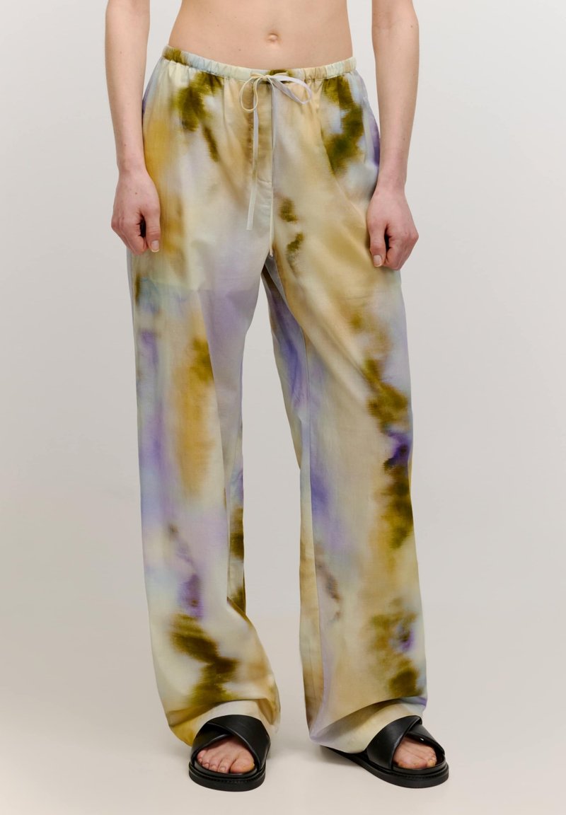Lichte broek in een tie-dye patroon met tinten geel, paars en blauw. Voorzien van een elastische tailleband en een trekkoord.