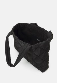 Black quilted tote bag with two fabric handles, featuring a smooth interior and an inner pocket. The exterior has a diamond pattern.