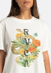 Bílý bavlněný tričko s barevným květinovým vzorem propleteným s hadími motivy a tučnými písmeny "RVCA" v černé barvě.