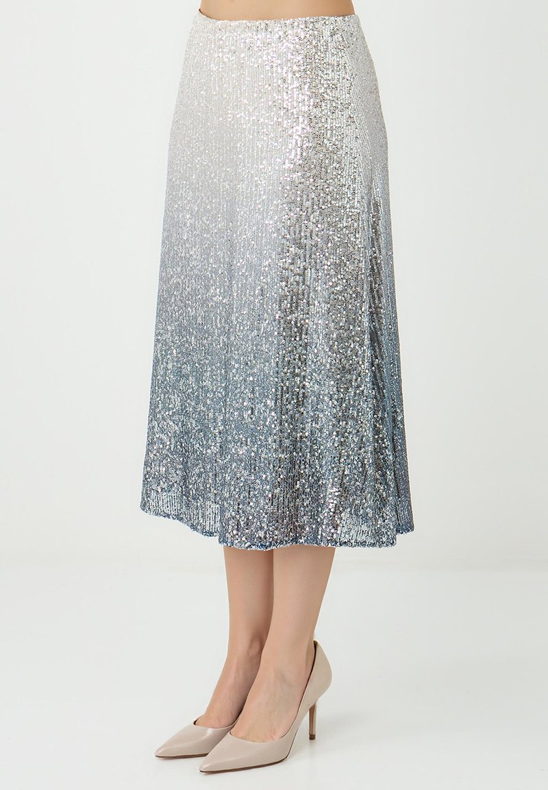 Jupe à sequins argentés avec un effet ombré, taille ajustée, silhouette en ligne A, et longueur au genou. Associée à des talons pointus couleur nude.