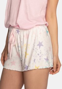 Shorts blancs avec des motifs d'étoiles colorés en rose, violet, jaune et teal. Présentent une taille élastique avec un cordon de serrage.