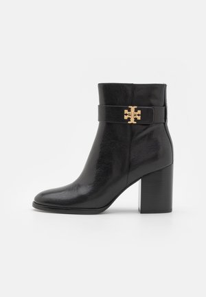 Bottine en cuir noir avec un bout arrondi, un talon bloc et une bande texturée avec un accent en logo doré. Fini de surface lisse.
