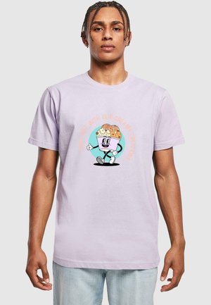 Light lavender t-shirt featuring a cartoon character with a dessert on its head, outlined in black, accompanied by playful text in orange and teal.