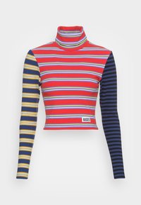 Turtleneck cropped top med rød, stribet krop og blå og gule accenter på den ene ærme. Materialet er ribbet, og mærket siger "RAGGED."