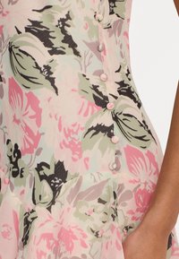 Floral dress in pastel colors with a soft texture. Features buttons along the side and a flared design, accentuated by a ruffled hem.