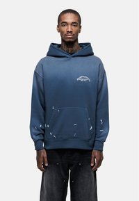 Felpa ombre blu in cotone con tasca frontale, logo grafico e accenti scoloriti; presenta un ampio cappuccio e polsini a costine.