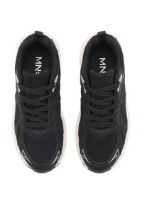 Črne atletske teniske iz mrežaste in sintetične materiala, z teksturirano zgornjim delom, trdnimi vezalkami in svetlo obarvanim gumijastim podplatom.