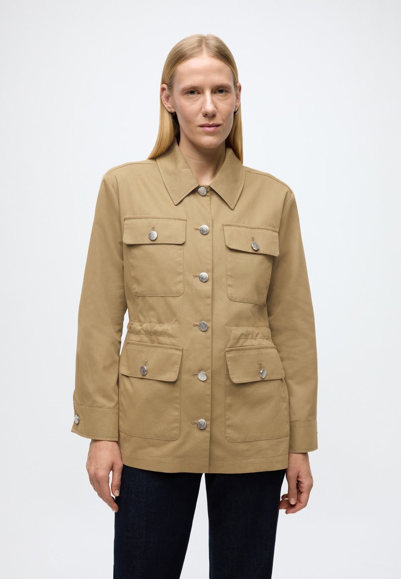Ljusbrun canvasjacka med krage, fyra framfickor, knappar i silverton och lätt insvängd midja. Skräddarsydd passform och långa ärmar.