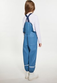 Mėlyni vandeniui atsparūs overalai su reguliuojamomis petnešomis, atspindinčiomis detalėmis ir elastingais kulkšnies kraštais. Pagaminti iš lygaus, lankstaus medžiagos.