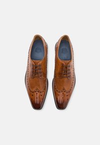 Scarpe eleganti in pelle marrone con punta affusolata, dettagli perforati e finitura liscia. Presentano una chiusura con lacci e una soletta impressa.