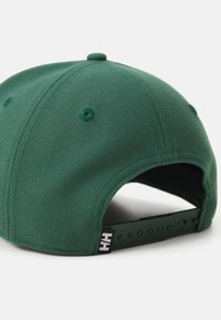 Zöld baseball sapka strukturált dizájnnal, texturált anyagból, állítható műanyag pánttal és logó címkével az oldalán.