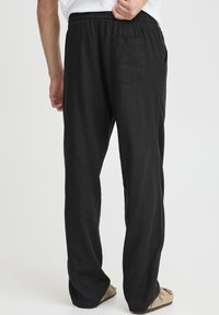 Sorte linnedbukser med løs pasform, elastik i taljen og en enkelt baglomme. Blød tekstur med rette ben.