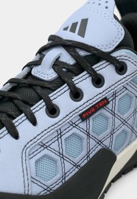 Pantof albastru deschis, cu texturi multiple, prezentând perforații hexagonale, șireturi negre și vârf întărit cu logo-ul roșu „FIVE TEN”.