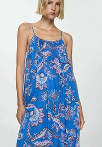 Maxikleid mit blauem Blumenmuster aus leichtem Stoff, mit Spaghetti-Trägern und lockerem Schnitt, verziert mit aufwendigen rosa und weißen Mustern.
