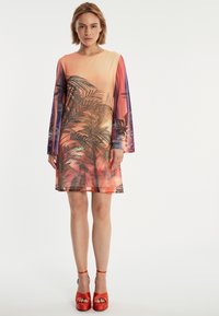 Robe à manches courtes avec un design dégradé dans des tons orange et rose, ornée de motifs de feuilles de palmier, et une coupe décontractée.