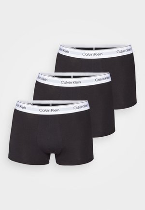 Boxer neri in cotone con cintura bianca che presenta il logo "Calvin Klein". Tre paia impilati ordinatamente, mostrando un tessuto liscio e elastico.