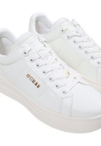 Baskets en cuir blanc avec un bout rond, des lacets plats et un logo "GUESS" doré sur le côté. Semelle en caoutchouc avec une texture lisse.