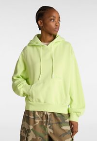 Neon green hoodie with a kangaroo pocket, drawstring hood, and ribbed cuffs. Paired with camouflage patterned pants.