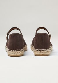Espadrillas in suede marrone con suola in juta intrecciata. Presentano una fibbia metallica sul cinturino posteriore. Texture liscia con dettagli minimi.