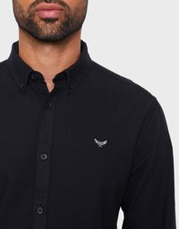 Camicia nera a maniche lunghe in cotone con colletto ripiegato e un piccolo logo ricamato bianco sul petto. Presenta bottoni frontali.