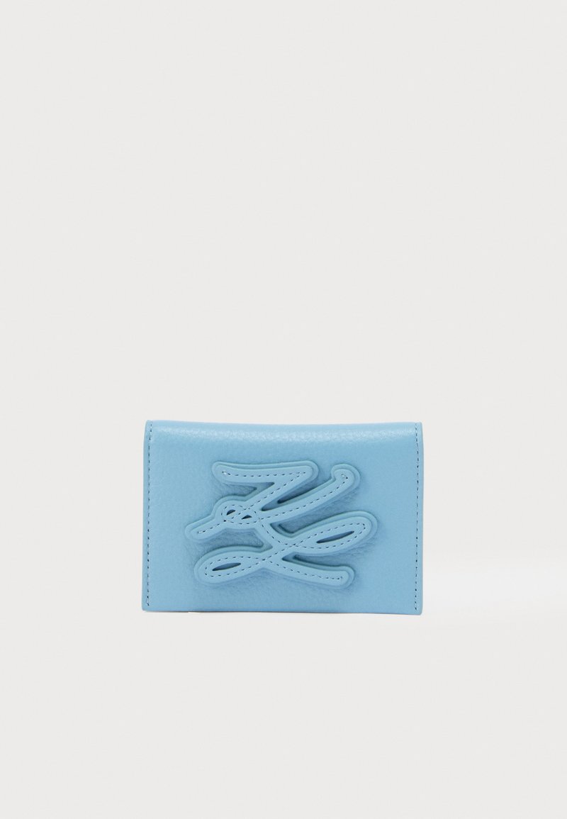Πορτοφόλι από δέρμα σε φωτεινό μπλε χρώμα με υφή και σχέδιο με ραφές. Διαθέτει ένα εμφανές αφηρημένο λογότυπο μπροστά και λεία επιφάνεια.