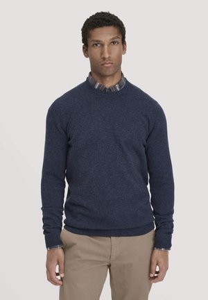 Marineblauer Strickpullover mit langen Ärmeln und Rundhalsausschnitt, über einem karierten Hemd getragen. Weicher Stoff und gerippte Bündchen sowie Saum.