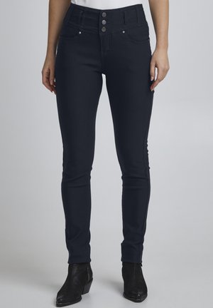 Tmavě modré skinny džíny s vysokým pasem, které mají tři kovové knoflíky a dvě přední kapsy. Hladká textura a těsně přiléhající střih.