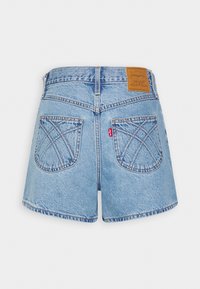 Vaaleansiniset farkkushortsit korkealla vyötäröllä, joissa on kaksi takataskua, joissa on ristipistokuvio, sekä ruskea nahkalappu takana.